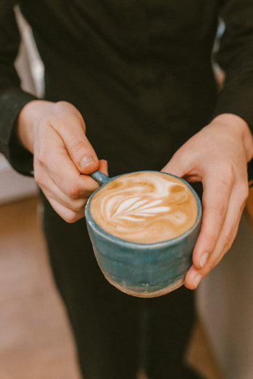blue tree gallery owner Aimee Rowland holding the best barista made coffee in a hand-made blue mug